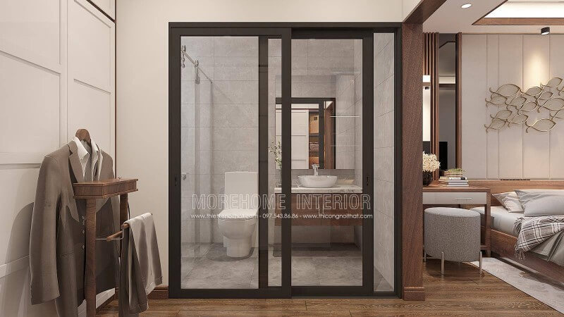 Trang trí nội thất phòng ngủ khép kín với xu hướng mở khi sử dụng tấm ốp tường gỗ óc chó như tạo ranh giới phân chia cùng thiết kế cửa kính trượt. Thiết kế nội thất phòng ngủ biệt thự